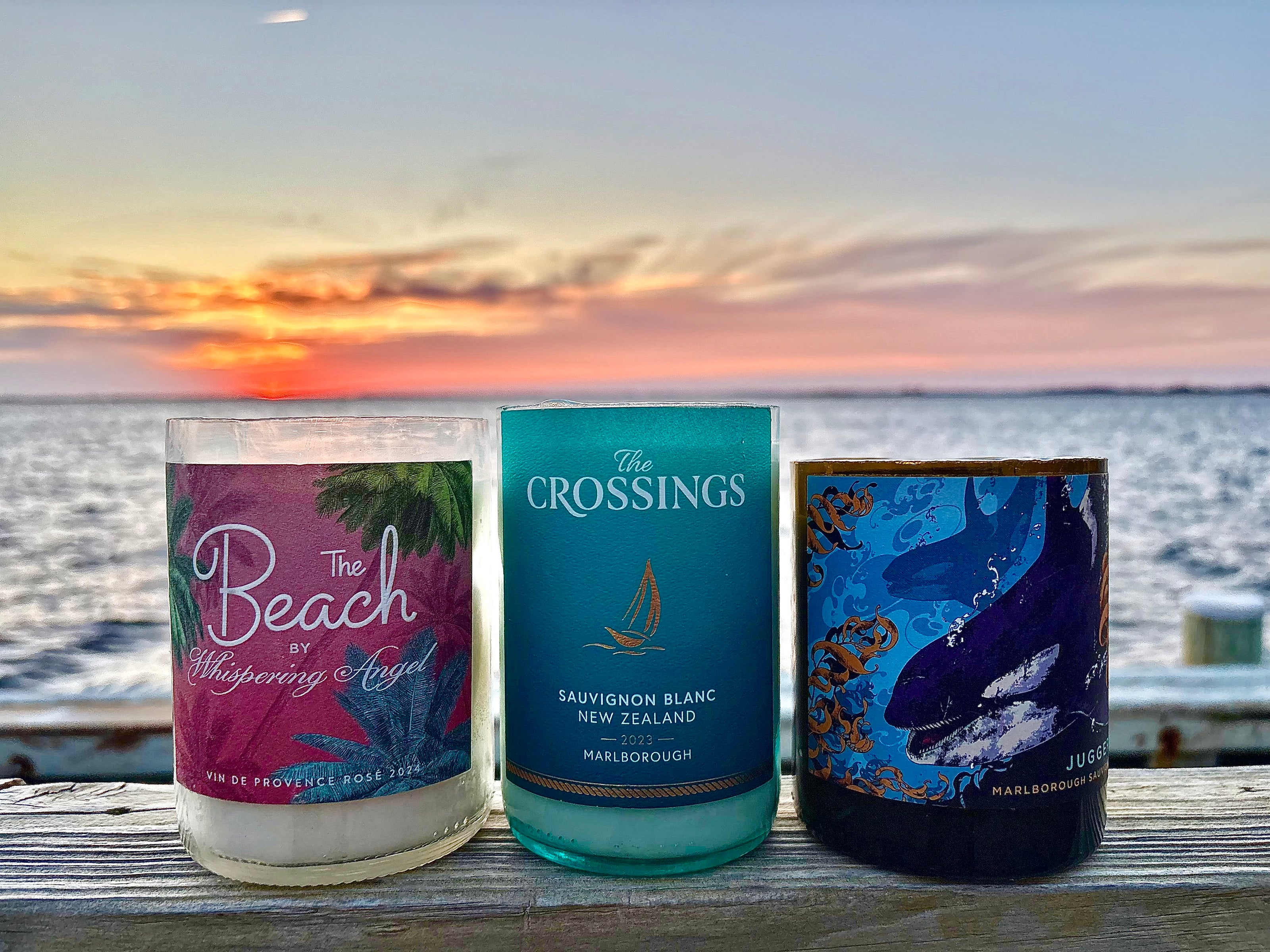 Three bottles of wine or similar products with scenic ocean view in the background